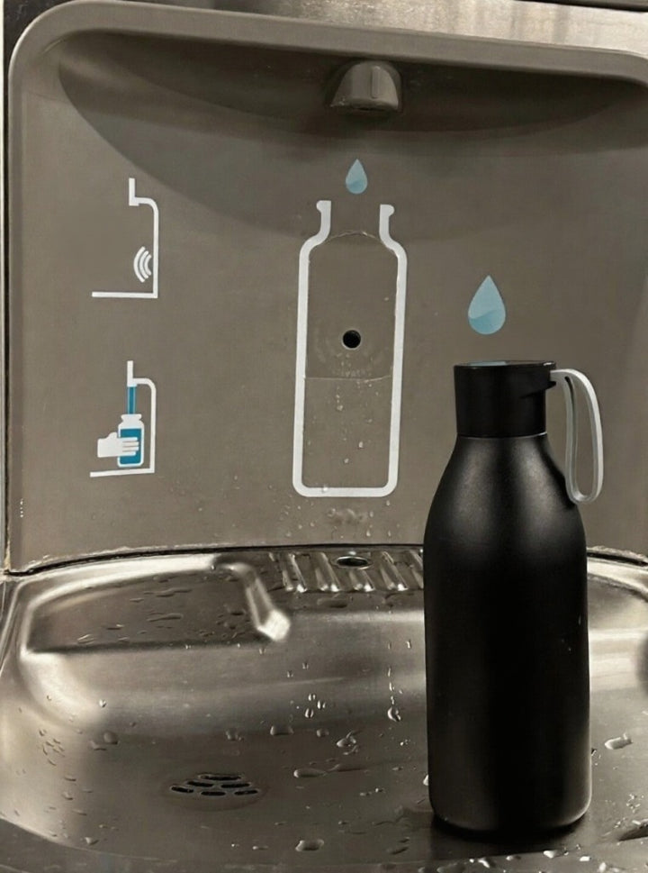 Black water bottle next to a sink with water droplet and bottle icons.